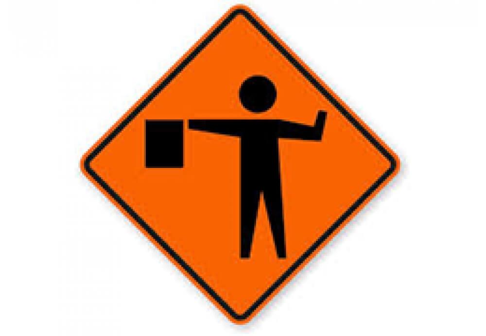 Work Zone Flagger directing traffic for safety compliance in construction. - Able Safety Consulting